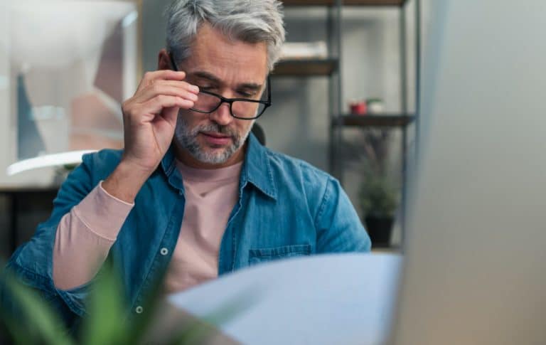 Mature man architect working on computer at desk indoors in office