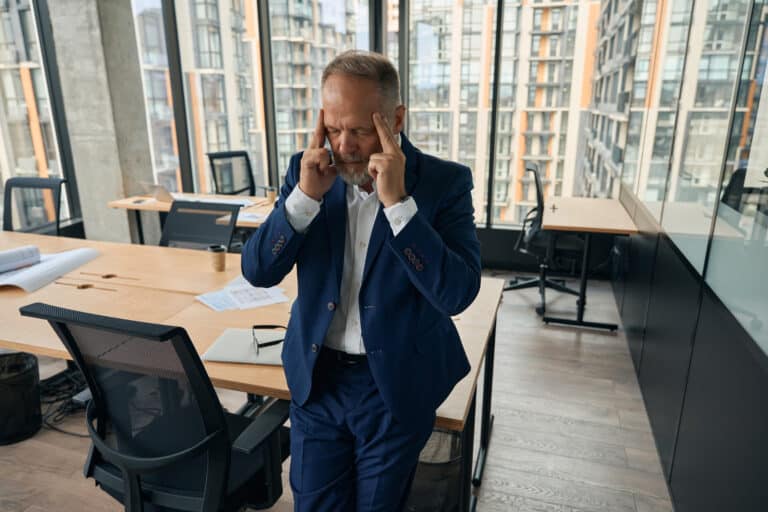 mature male office manager having haedache after dealing with documents